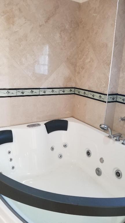 a white bath tub in a bathroom with a tile wall at RENTAL FLAT BOUTIQUE PILAR in Pilar