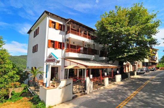 a white building with a restaurant on the side of a street at Komninos Rooms in Panagia