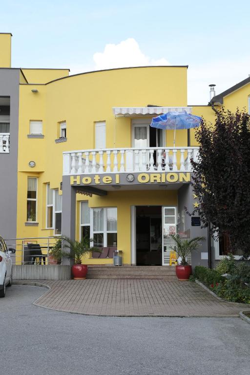 a yellow building with a hotel entrance with an umbrella at Hotel Orion in Ivanec