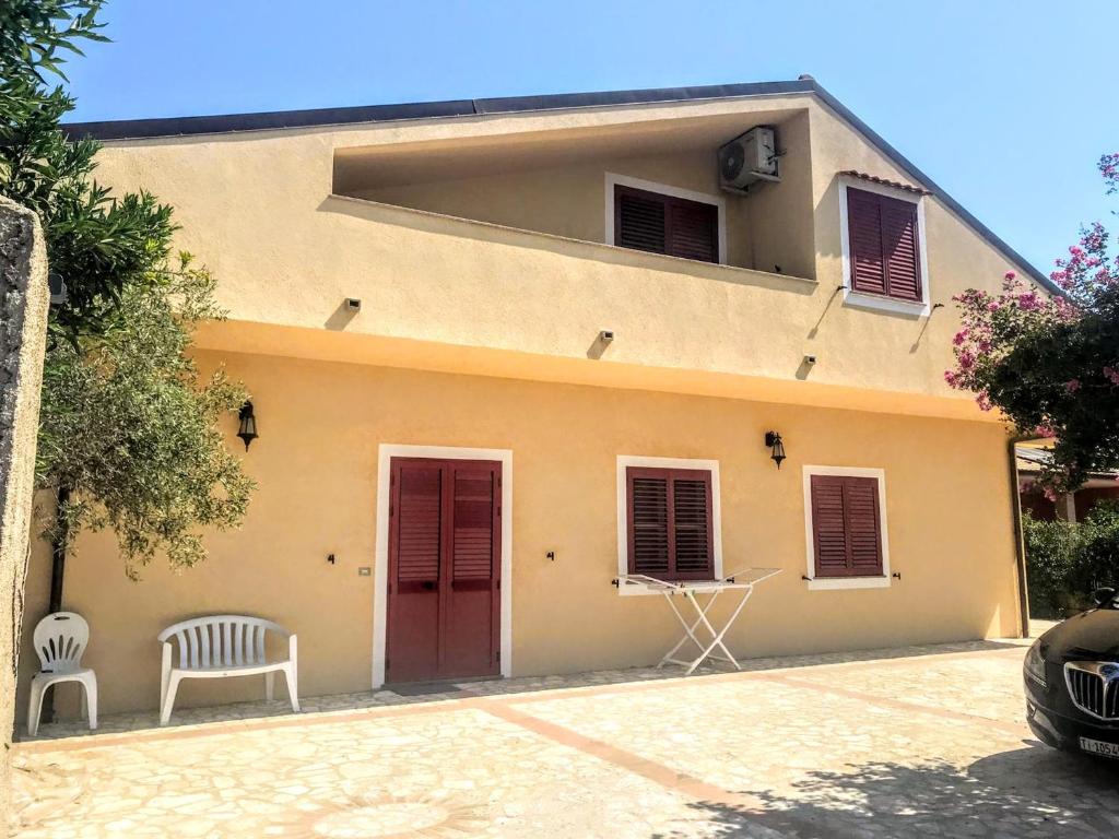 uma casa com uma porta vermelha e uma cadeira branca em Casa di Vacanza Marina di Davoli em Marina di Davoli