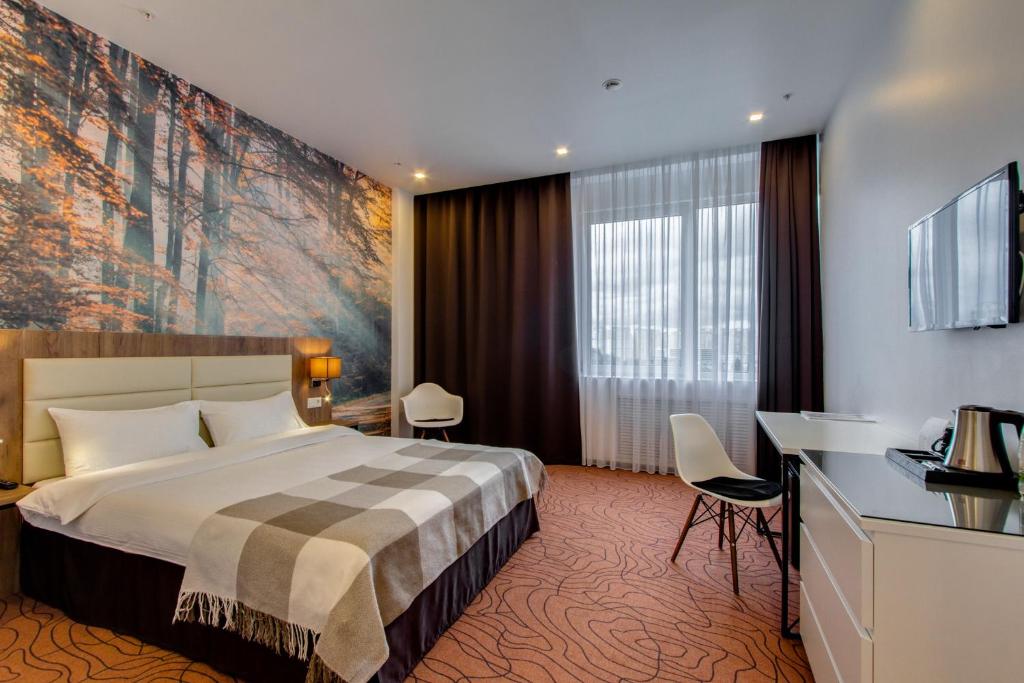 a hotel room with a bed and a large painting on the wall at Sunflower Hotel Vnukovo in Moskovsky