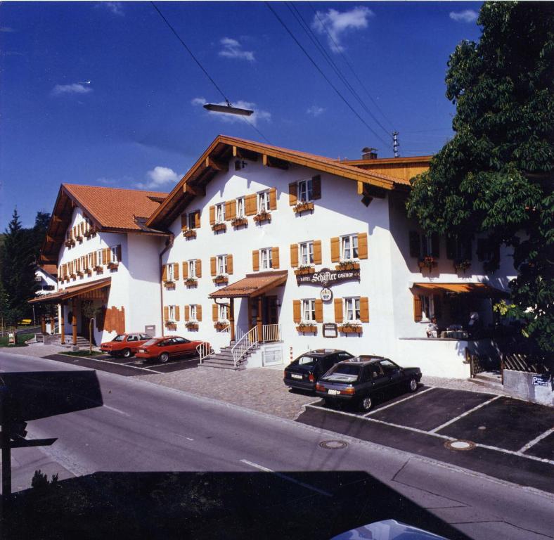 un gran edificio blanco con coches aparcados en un aparcamiento en Hotel Gasthof Schäffler en Sonthofen