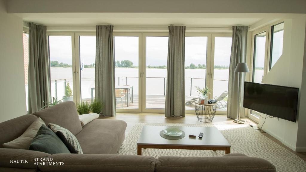 a living room with a couch and a large window at Luxuswohnung Pazifik WESER WELLNESS WHIRLPOOL in Brake