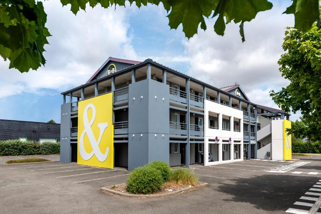 un edificio de oficinas con un edificio amarillo y gris en B&B HOTEL Angers 1 Beaucouzé, en Beaucouzé