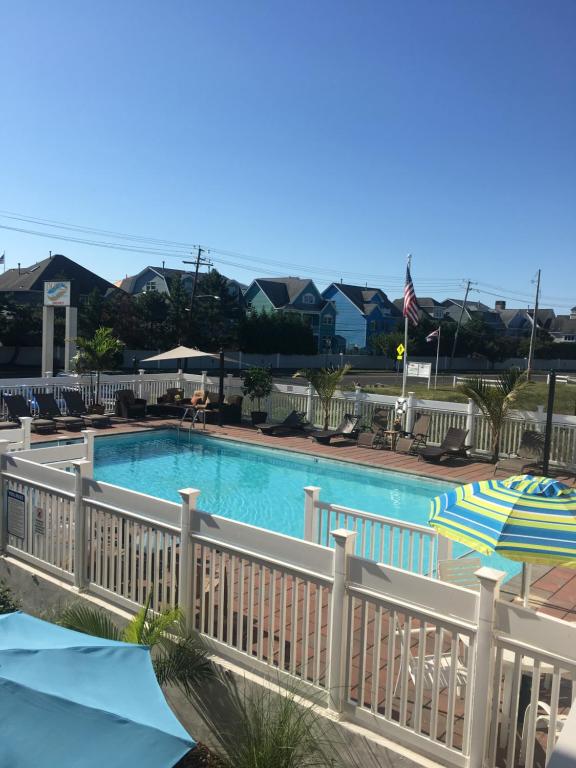 a swimming pool with a fence and an umbrella at Dunes by the Ocean in Point Pleasant Beach