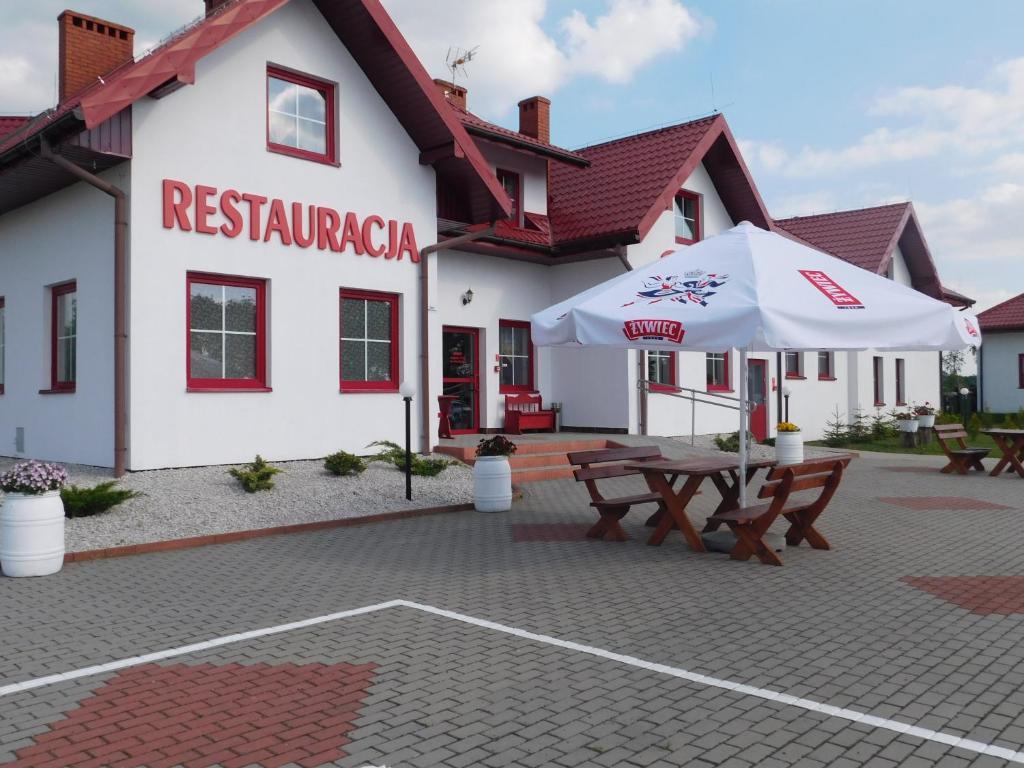 un ristorante con tavoli e ombrelloni di fronte a un edificio di Potok 5 a Złoczew