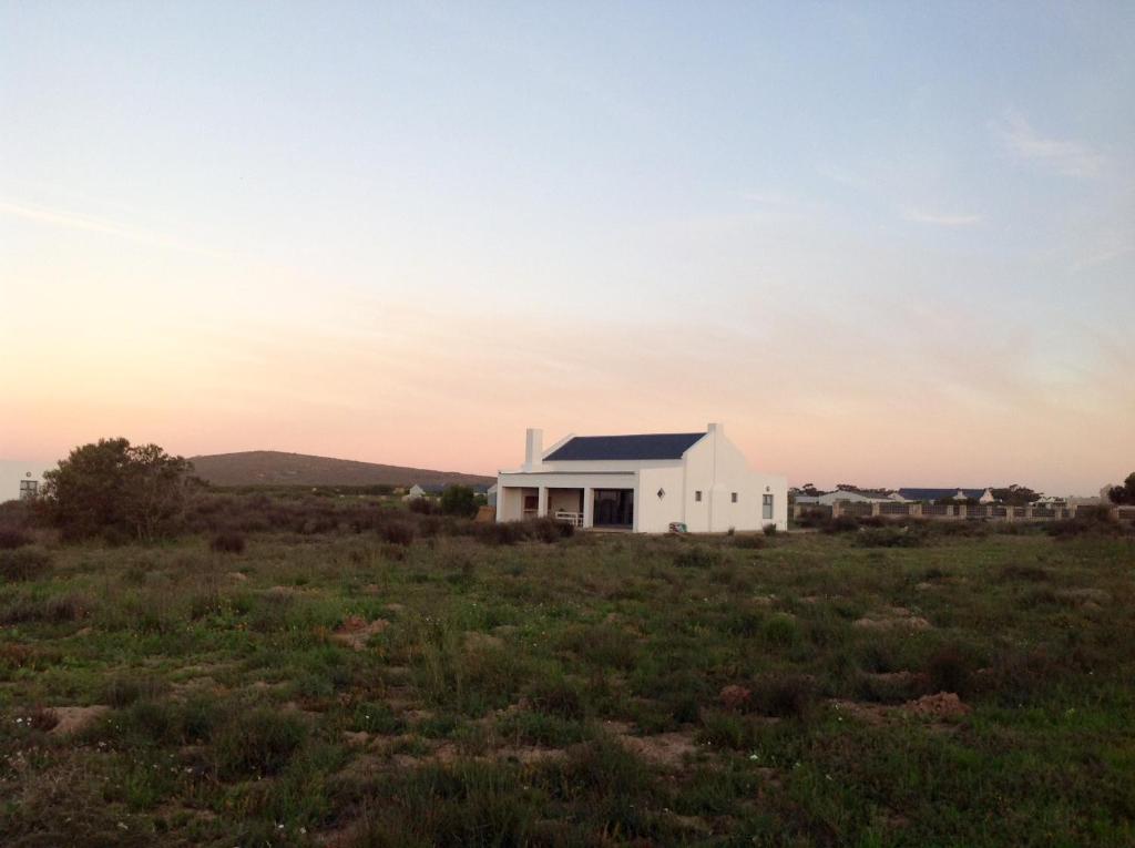 a white house in the middle of a field at Camelot Cottages in Langebaan