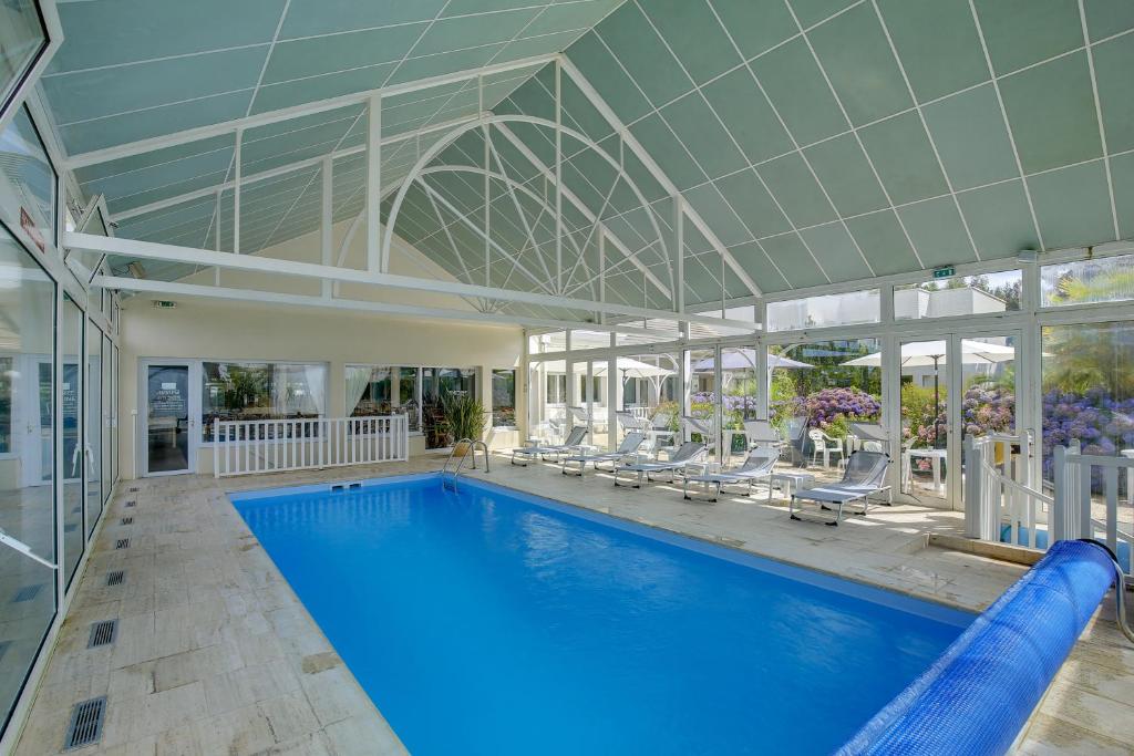 une piscine intérieure avec des chaises et un grand plafond dans l'établissement Hôtel Arcadia, à Lannion