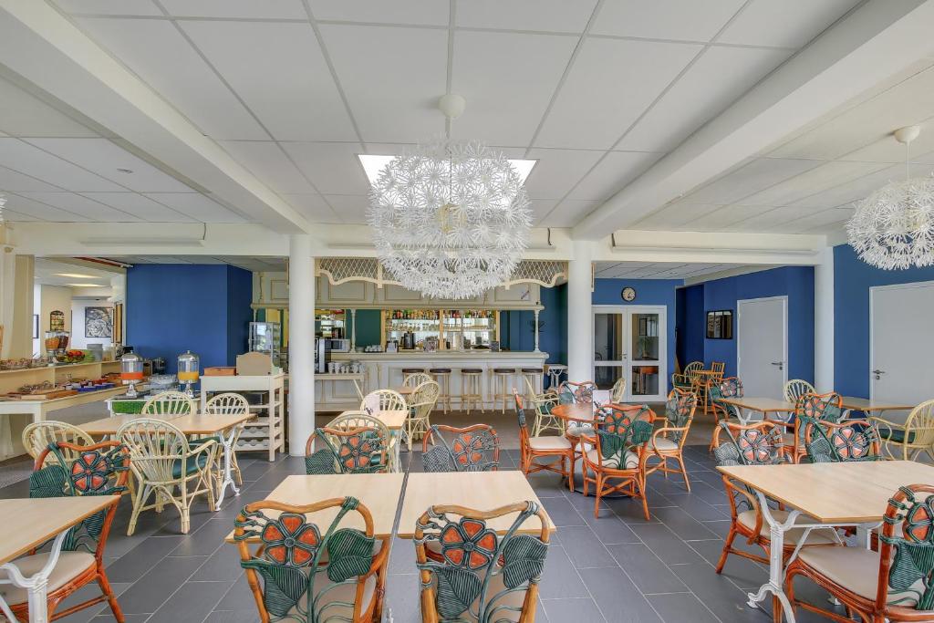 a restaurant with blue walls and tables and chairs at Hôtel Arcadia in Lannion