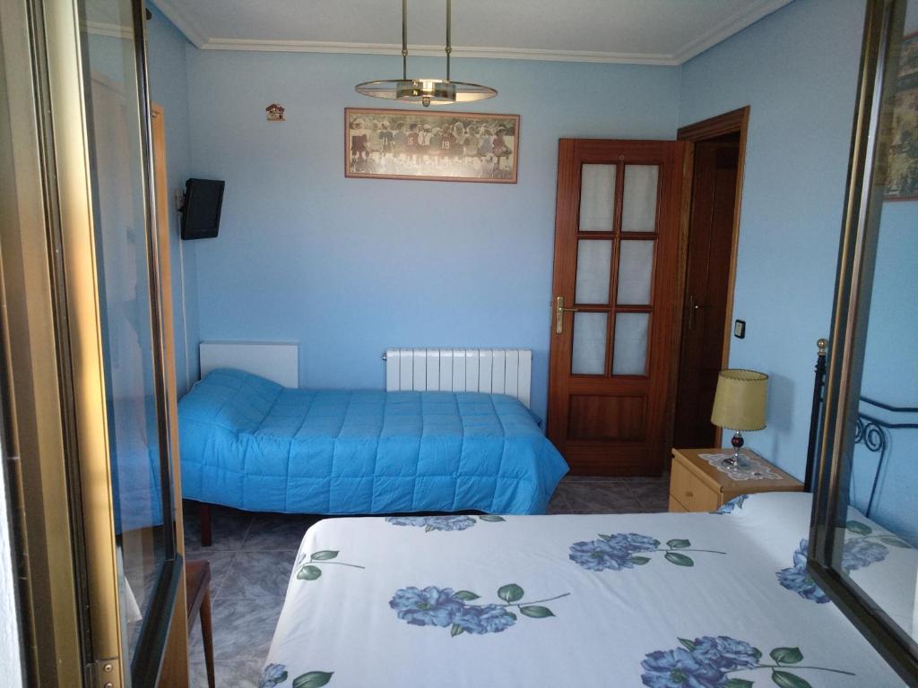 um quarto com 2 camas e um quarto azul em Casa Rural El Carrascal em Valdefuentes de Sangusín