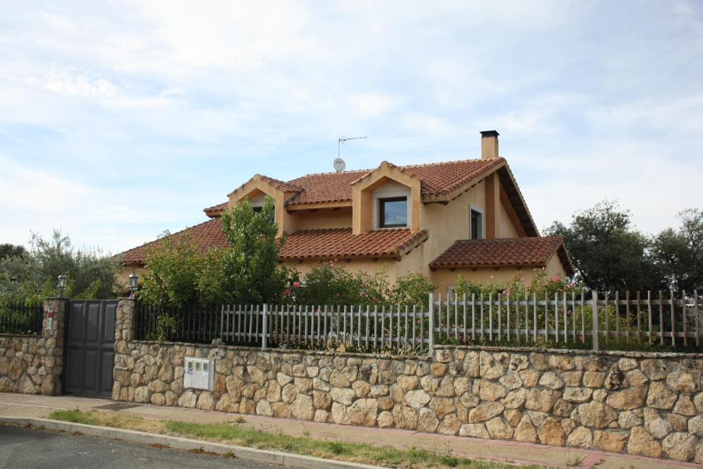 una casa detrás de una pared de piedra con una valla en Villa Miranda, en Carrascal de Barregas