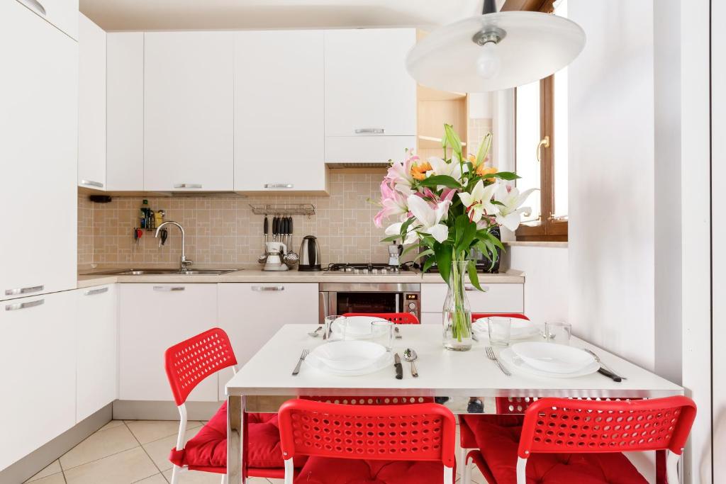 kuchnia z czerwonymi krzesłami i stołem z wazonem kwiatów w obiekcie Corsica Huge Terrace Flats w Mediolanie