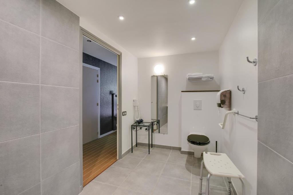 a white bathroom with a toilet and a mirror at Hôtel Arcadia in Lannion