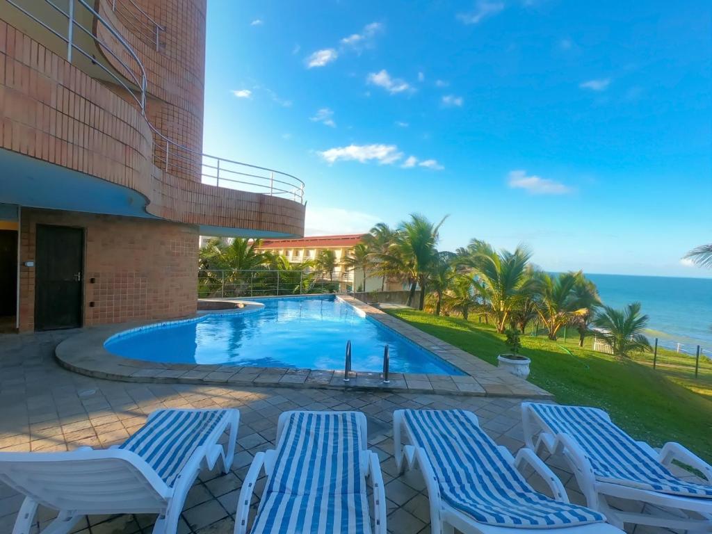 納塔爾的住宿－Costeira Praia Flat 204，一个带2把躺椅的游泳池和海洋