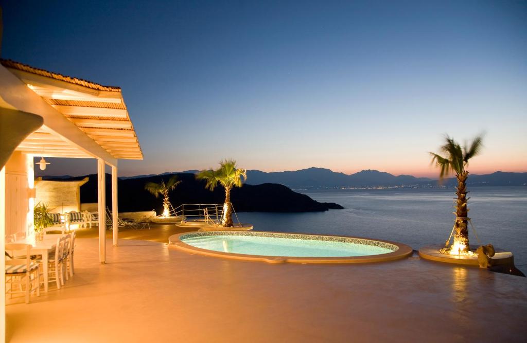 a swimming pool on a patio with a view of the ocean at Villa Achilleas Crete in Ierápetra