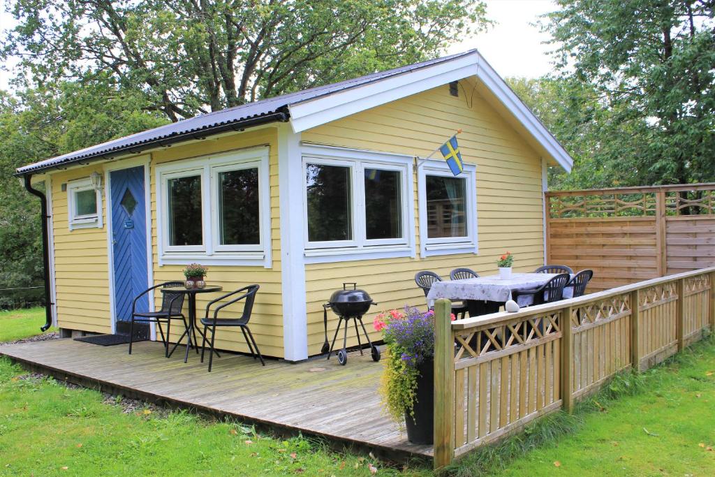 a yellow cabin with a table and chairs on a deck at Naturnära STUGA ULLARED in Ullared