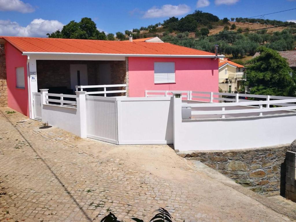 een roze huis met een wit hek ervoor bij Casa do Forno do Ti Correia in Macedo de Cavaleiros