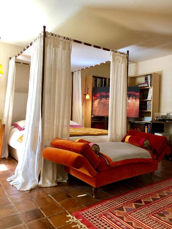 a bedroom with a canopy bed with an orange couch at La Maison d&#39;Alice in Vézac