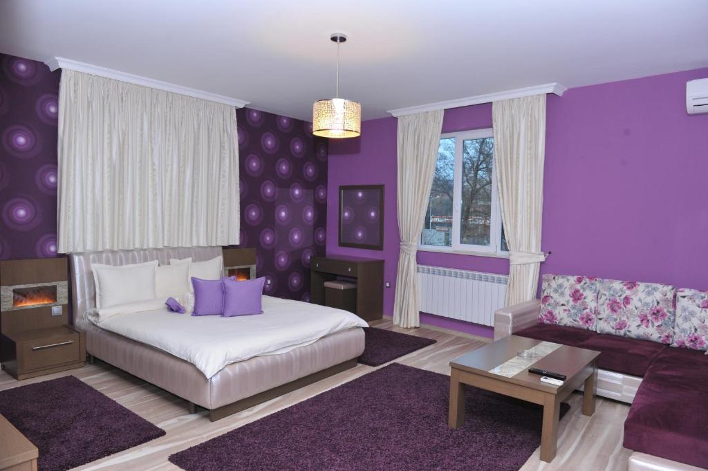Dormitorio púrpura con cama y sofá en Eros Motel, en Sandanski