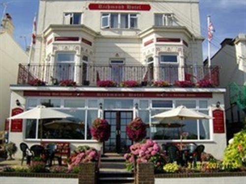 a white building with tables and umbrellas in front of it at Richmond Hotel in Weston-super-Mare