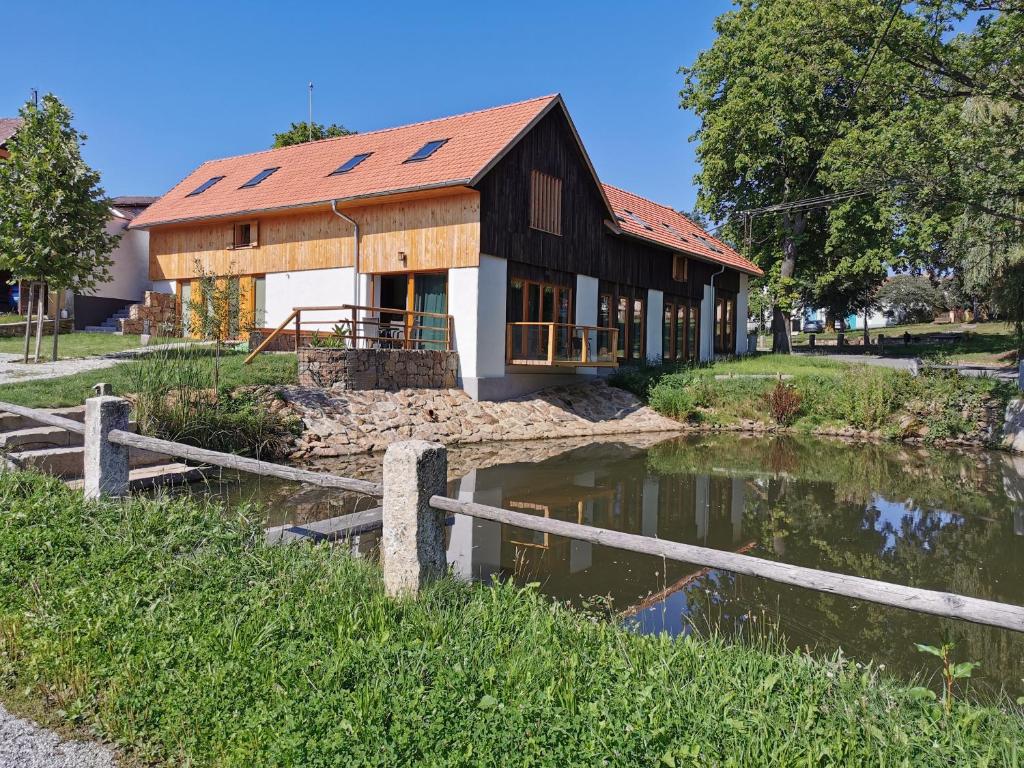 Um celeiro com um lago à frente. em Penzion Okamžik Stanovice em Nová Cerekev