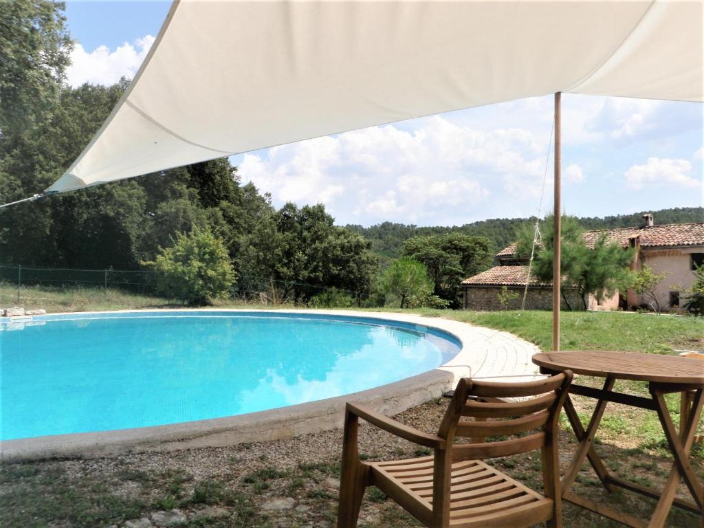 - une table et des chaises avec un parasol à côté de la piscine dans l'établissement Domaine Saint-Jaume gîte Cinsault, à Barjols