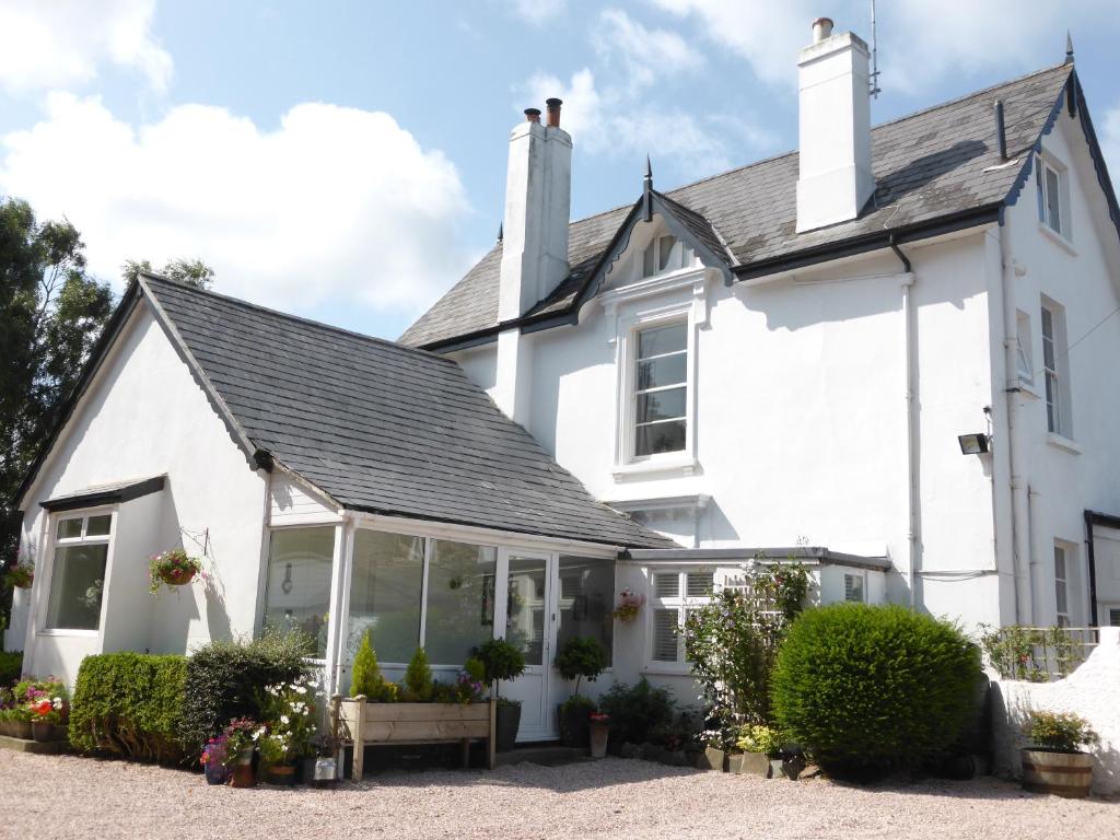 una casa blanca con un salón acristalado delante de ella en Cookshayes Country Guest House en Moretonhampstead