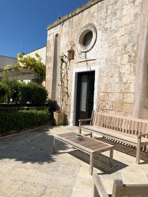 a wooden bench and a table in front of a building at Villa Romasi in Leuca