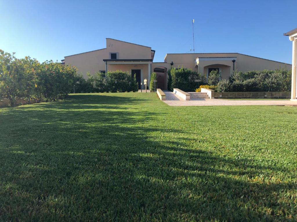 una casa con un gran césped delante de ella en Podere San Luigi Residence, en Otranto