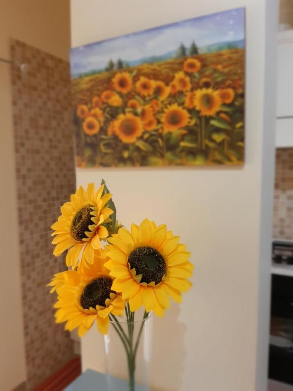 a group of yellow flowers in a vase next to a painting at A DUE PASSI DAL BLU in Marina di Gioiosa Ionica