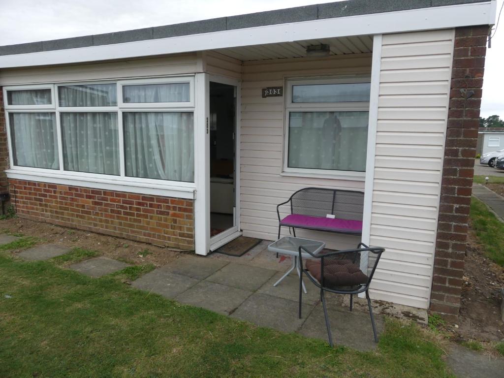 a house with a bench and a chair on a patio at 303 Sundowner in Hemsby