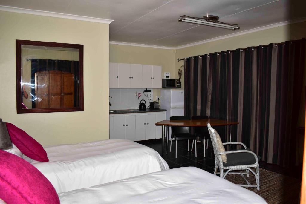 a room with two beds and a table and a kitchen at 13 Hobson in Secunda