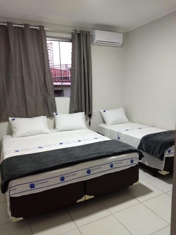 two beds in a room with a window at Hotel Flor Paulista in São Paulo