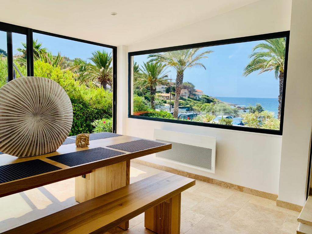 a living room with a table and large windows at Maison en front de mer sur la plage de portissol in Sanary-sur-Mer