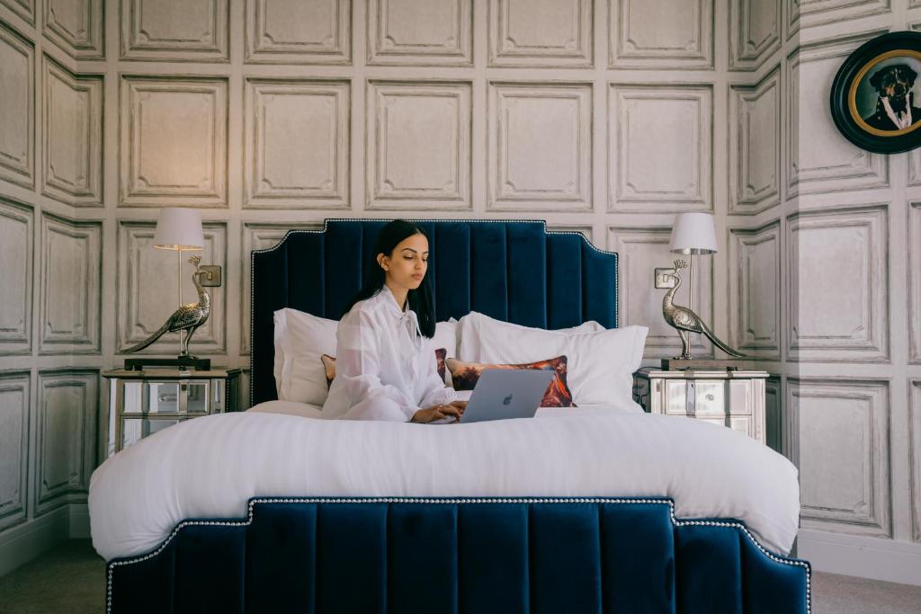 una mujer sentada en una cama con un portátil en Rowan Tree - Your Apartment en Bristol