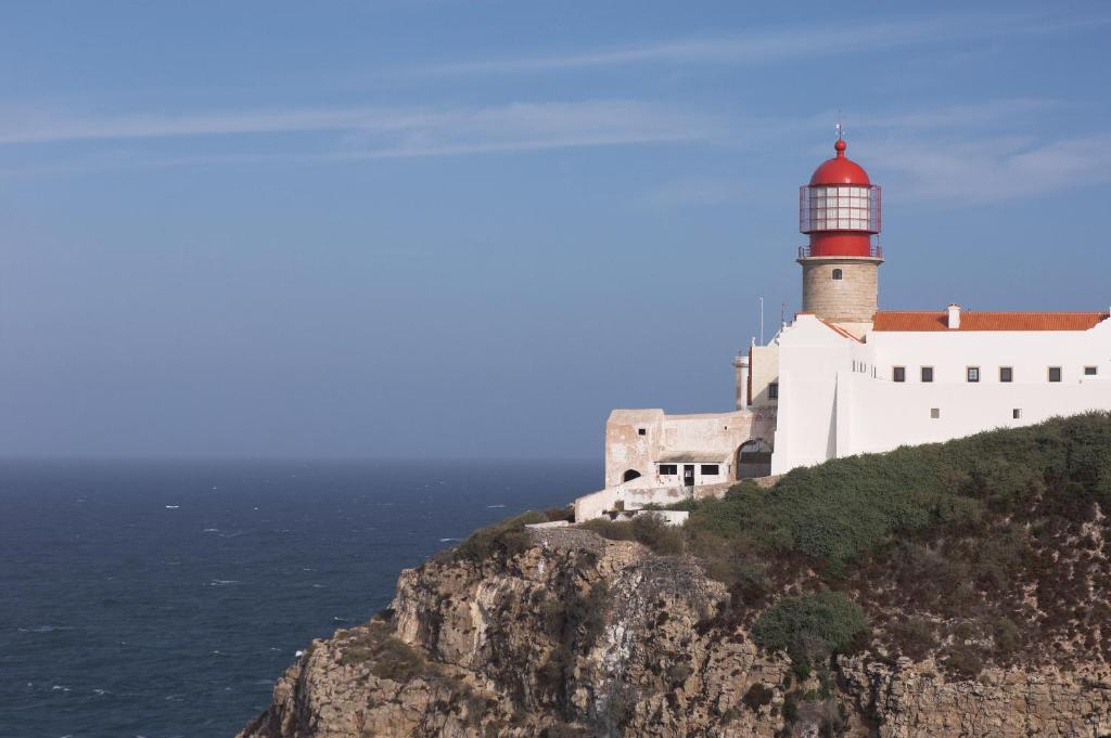 a lighthouse on a cliff next to the ocean at Sagres Time Apartamentos in Sagres