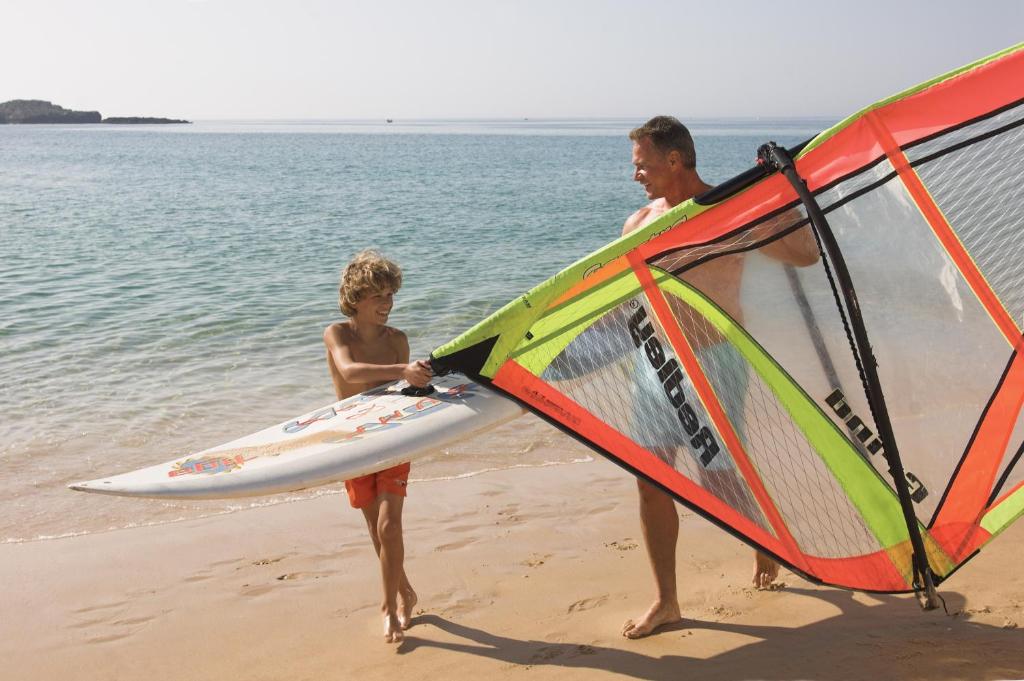 a man and a young girl holding a wind sail on the beach at Sagres Time Apartamentos in Sagres