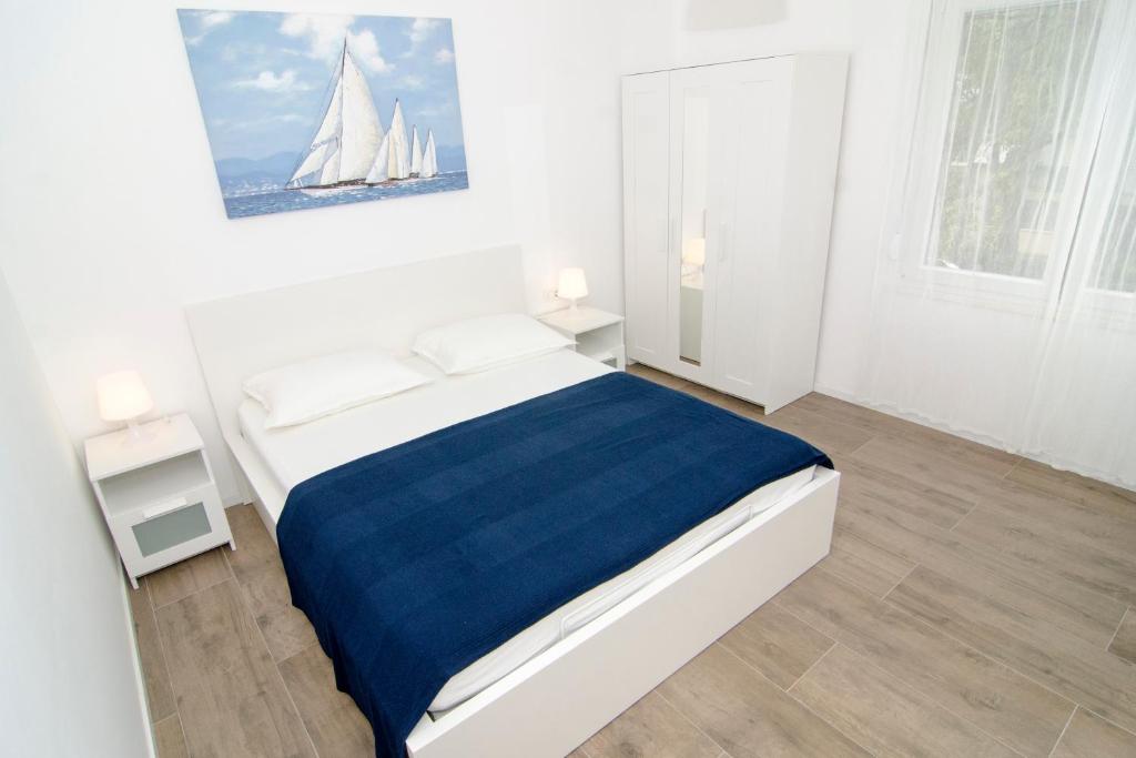 a white bedroom with a bed with a sailboat on the wall at Apartman M&D in Split