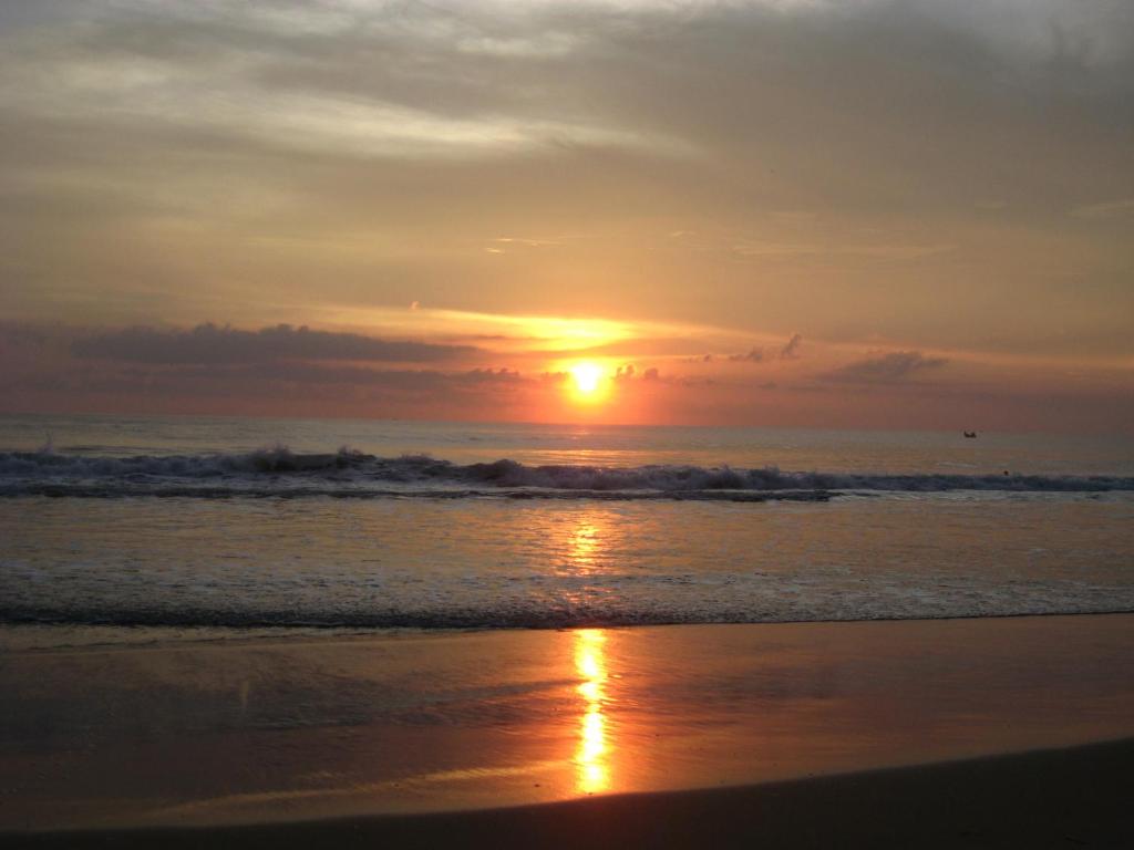 a sunset on the beach with the ocean at Jickys Nest in Varkala