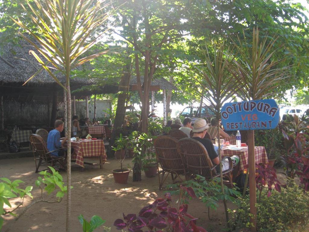 a group of people sitting at tables in a restaurant at Jickys Nest in Varkala