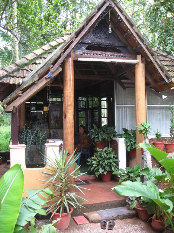 a man sitting on a porch of a house with plants at Jickys Nest in Varkala