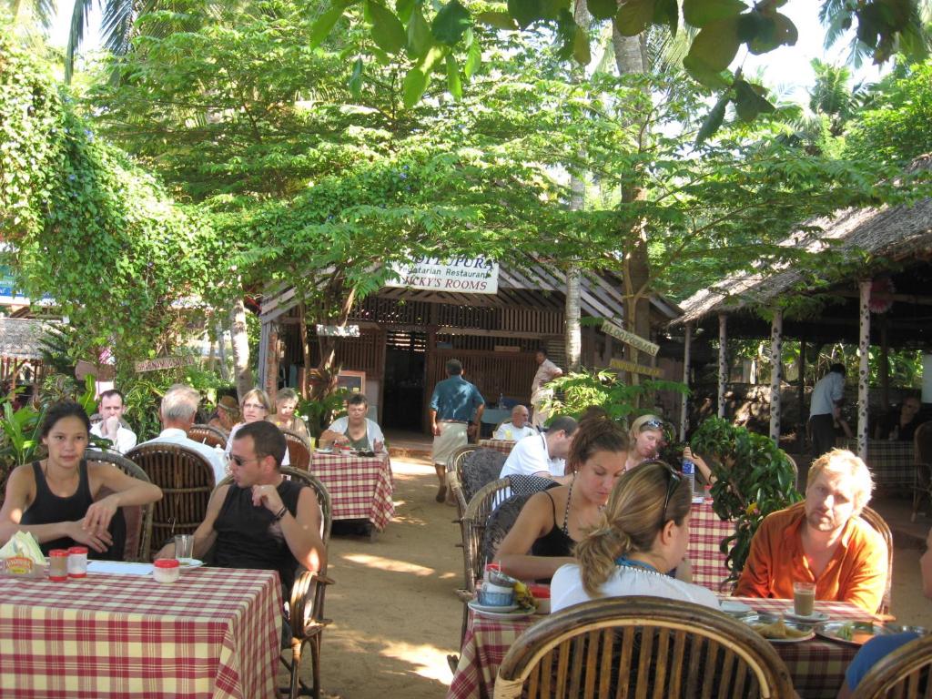 a group of people sitting at tables in a restaurant at Jickys Nest in Varkala