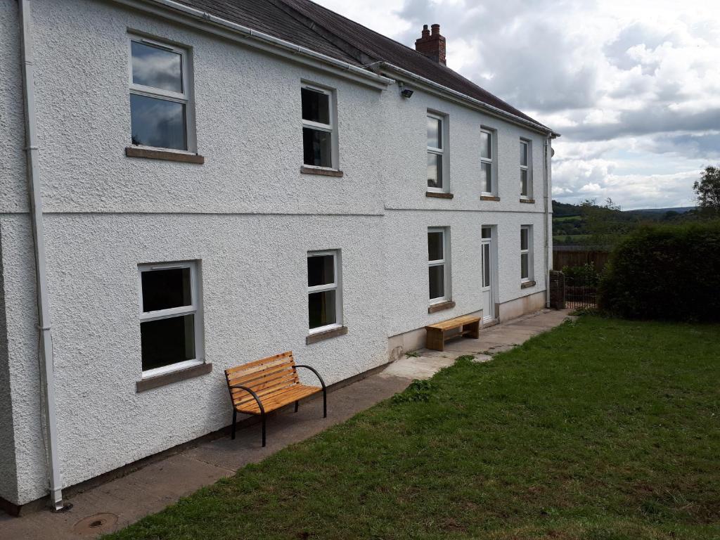 a white building with a bench in front of it at Llandeilo Farmhouse in Llandeilo