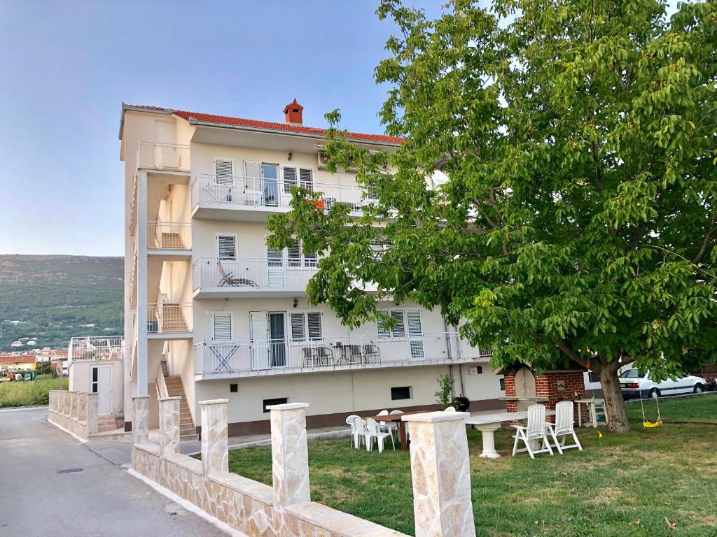 ein Gebäude mit Stühlen und einem Baum davor in der Unterkunft Apartmani Dujmovic in Kaštela