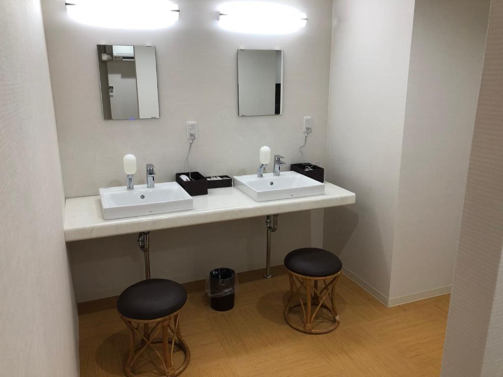 La salle de bains est pourvue de 2 lavabos et de 2 tabourets. dans l'établissement Hotel Hikari Hills, à Shunan