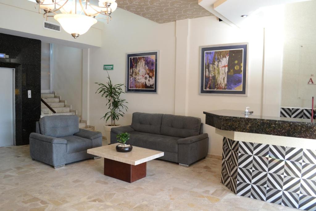eine Lobby mit 2 Stühlen, einem Tisch und einer Theke in der Unterkunft Hotel America Centro in Los Mochis