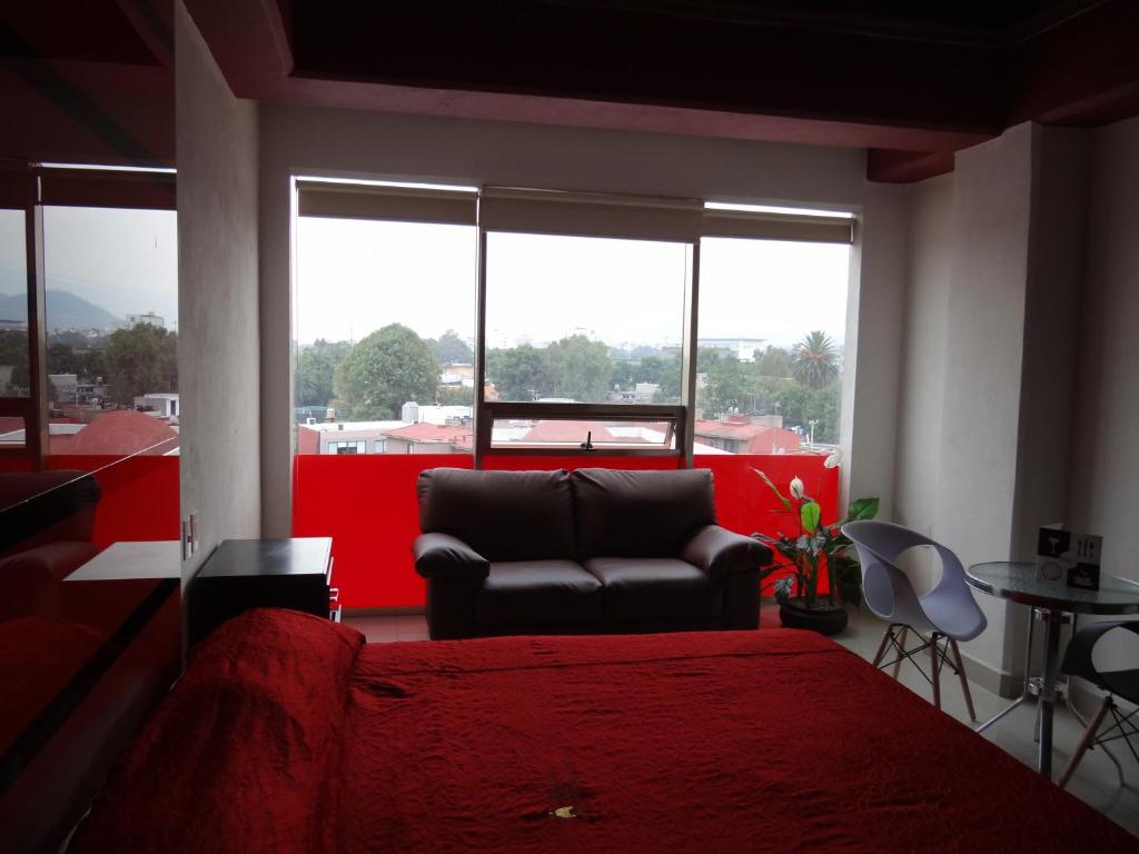 1 dormitorio con cama roja, sofá y ventanas en Hotel Quinta Tlalpan en Ciudad de México