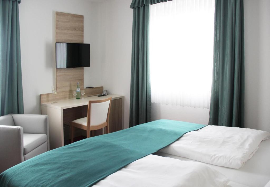 a bedroom with a bed and a desk and a chair at Stadthotel Alsfeld in Alsfeld