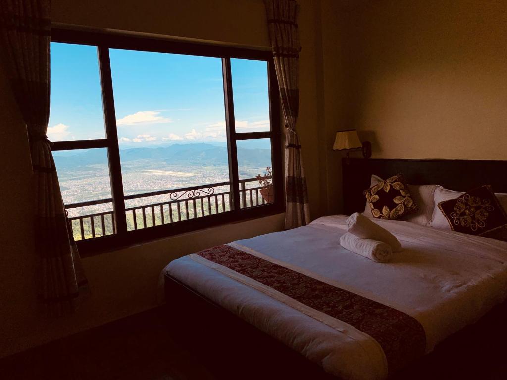 um quarto com uma cama e uma janela grande em Superview Lodge, Best Himalayan Sunrise in Sarangkot em Pokhara