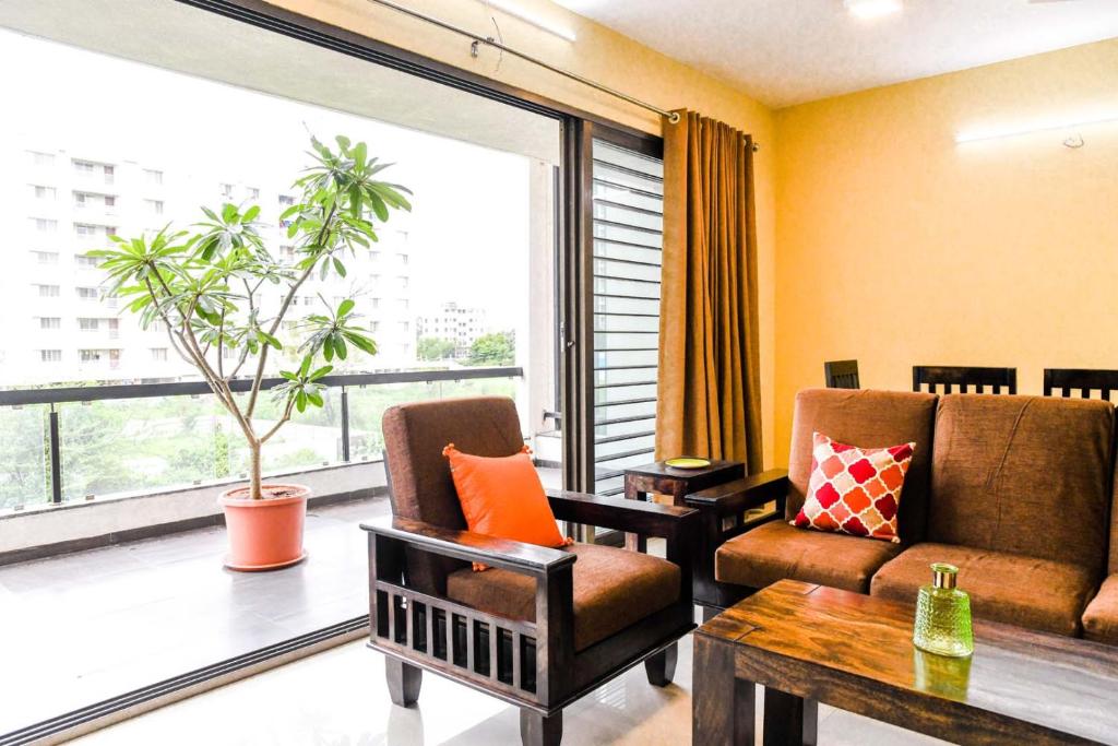 ナーシクにあるStatus Homeaway Service Apartmentsのリビングルーム(ソファ、椅子、大きな窓付)